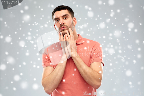 Image of young man touching his face over snow background