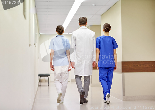 Image of group of medics or doctors walking along hospital