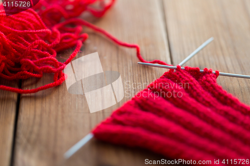 Image of hand-knitted item with knitting needles on wood