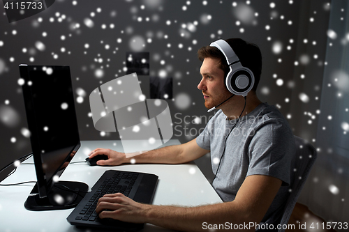 Image of man in headset playing computer video game at home