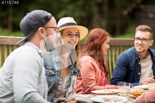 Image of happy friends having dinner at summer garden party