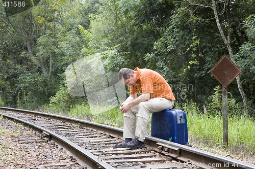 Image of Man sitting on railroad track