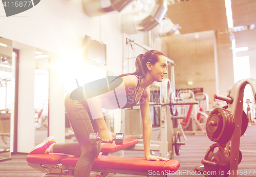 Image of happy woman with dumbbell flexing muscles in gym