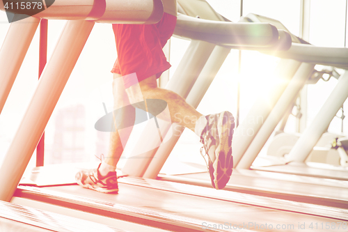 Image of close up of male legs running on treadmill in gym