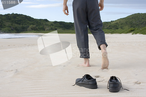 Image of Businessman barefoot on beach