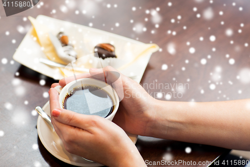 Image of close up of woman holding coffee cup and dessert