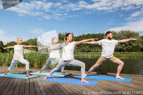 Image of group of people making yoga exercises outdoors