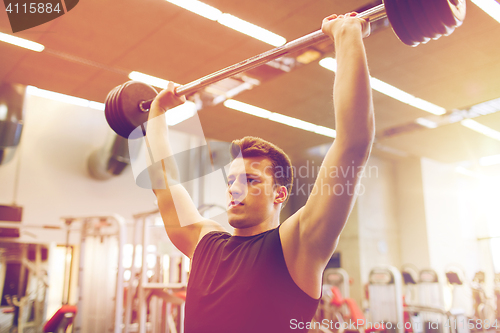 Image of young man flexing muscles with barbell in gym