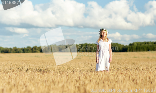 Image of happy young woman in flower wreath on cereal field