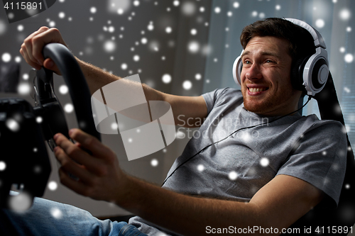 Image of man playing car racing video game at home