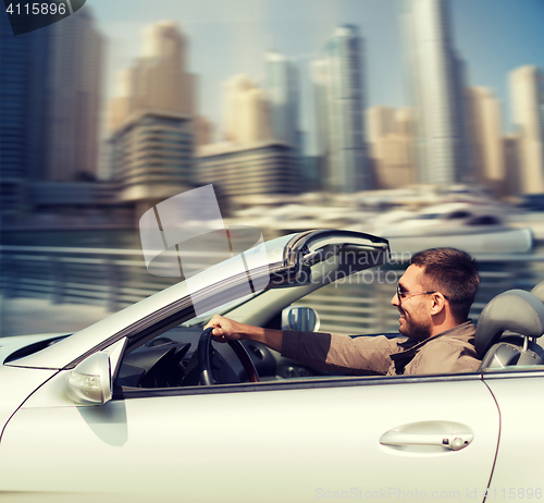 Image of happy man driving cabriolet car on city 