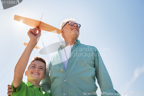 Image of senior man and boy with toy airplane over sky