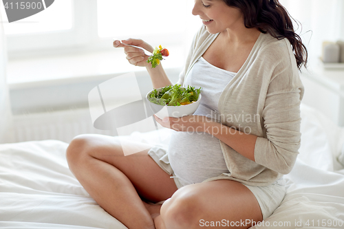 Image of close up of pregnant woman eating salad at home