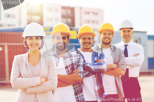 Image of group of smiling builders in hardhats outdoors