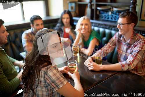 Image of happy friends drinking beer at bar or pub