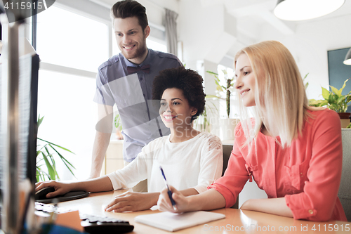 Image of happy creative team with computer in office