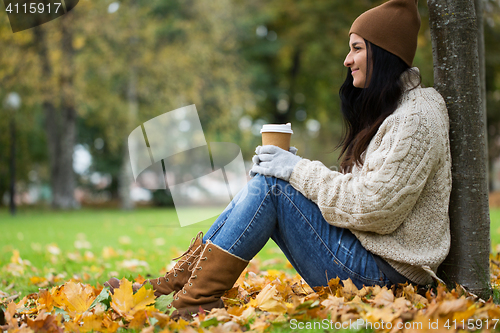 Image of close up of woman drinking coffee in autumn park