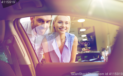 Image of happy couple buying car in auto show or salon