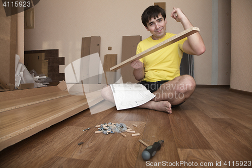 Image of Young man assembling furniture