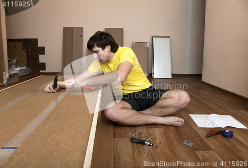 Image of Young man assembling furniture