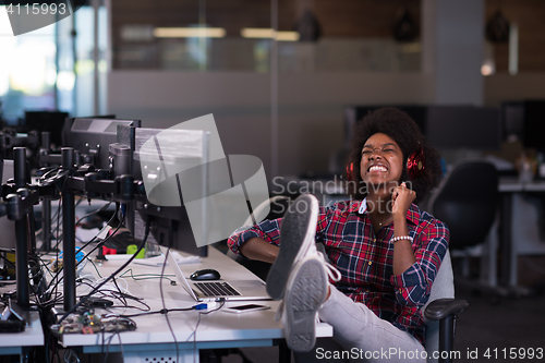 Image of woman at her workplace in startup business office listening musi