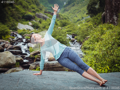 Image of Woman doing yoga asana Vasisthasana - side plank pose outdoors