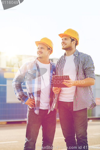 Image of smiling builders with tablet pc outdoors