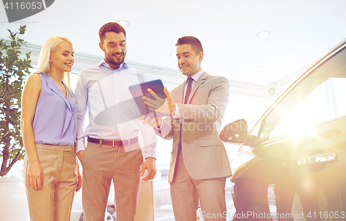 Image of happy couple with car dealer in auto show or salon