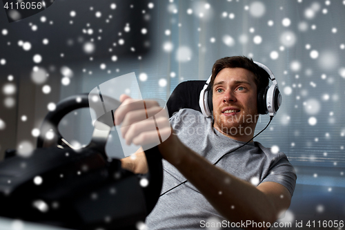 Image of man playing car racing video game at home