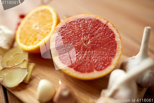 Image of citrus fruits, ginger and garlic on wood