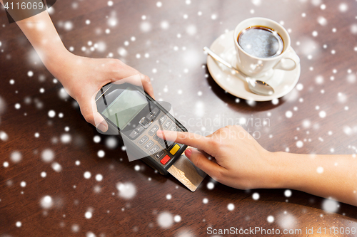 Image of close up of hands with credit card reader at cafe