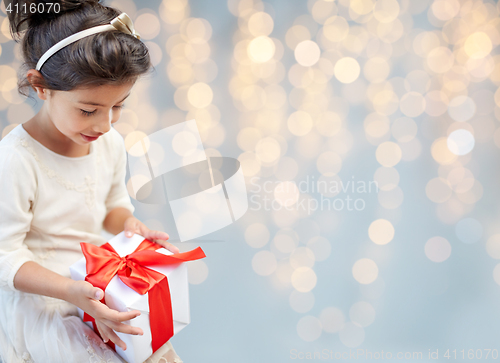 Image of smiling little girl with gift box over lights