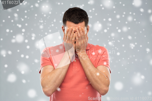 Image of man covering his face with hands over snow