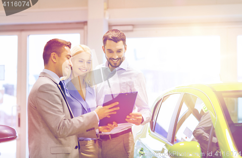 Image of happy couple with car dealer in auto show or salon