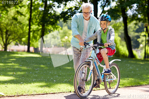 Image of grandfather and boy with bicycle at summer park