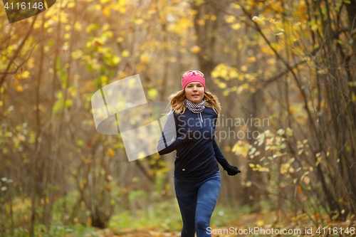 Image of Woman running among autumn leaves