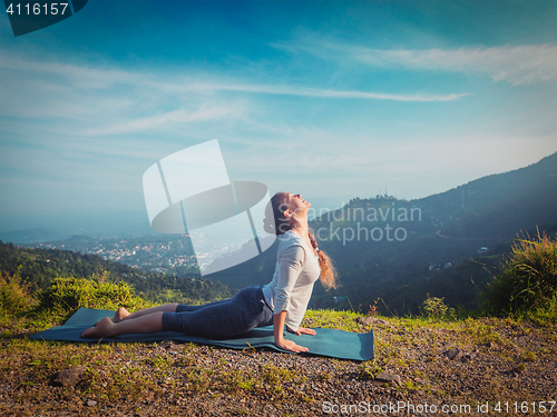 Image of Woman practices yoga asana Urdhva Mukha Svanasana outdoors