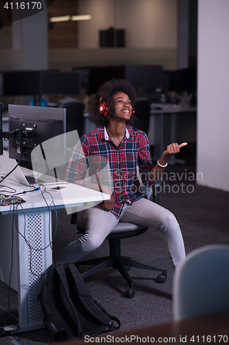 Image of woman at her workplace in startup business office listening musi