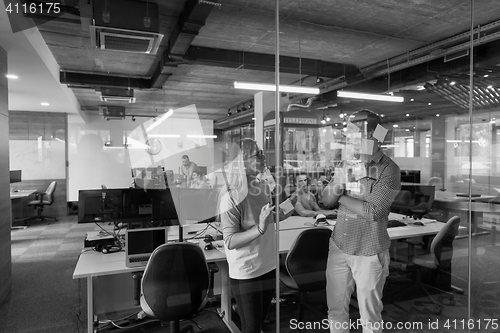 Image of young couple at modern office interior writing notes on stickers