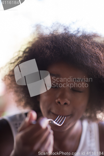 Image of a young African American woman eating pasta