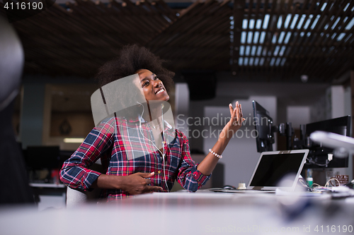 Image of woman at her workplace in startup business office listening musi