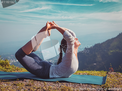 Image of woman doing Ashtanga Vinyasa Yoga asana Dhanurasana - bow pose