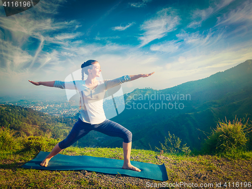 Image of Woman doing yoga asana Virabhadrasana 2 - Warrior pose outdoors