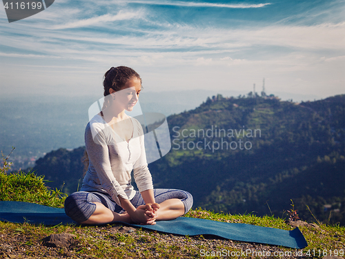 Image of Sporty fit woman practices yoga asana Baddha Konasana outdoors