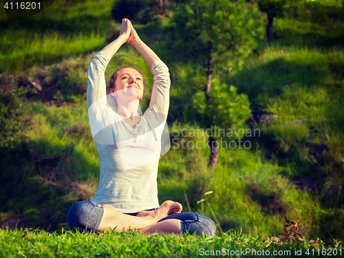 Image of Young sporty fit woman doing yoga Lotus pose oudoors 