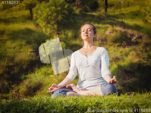 Image of Young sporty fit woman doing yoga Lotus pose oudoors 