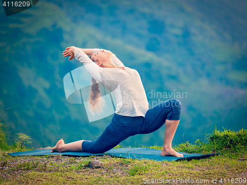 Image of Sporty fit woman practices yoga asana Anjaneyasana in mountains