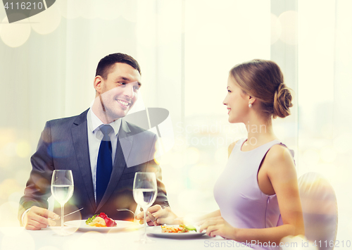 Image of smiling couple eating main course at restaurant