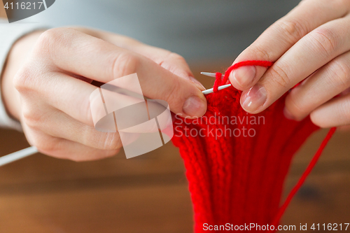 Image of close up of hands knitting with needles and yarn