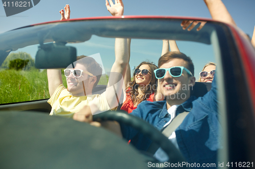 Image of happy friends driving in cabriolet car at country